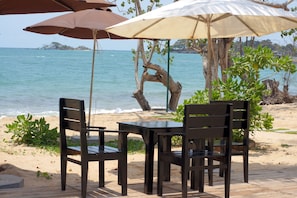 A beachside table with chairs and umbrellas, overlooking the sea. - Gold Sand Beach Bungalow (Phu Quoc)