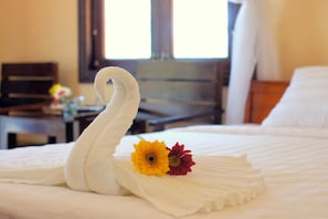 A bed with a swan-shaped towel and two flowers. - Gold Sand Beach Bungalow (Phu Quoc)