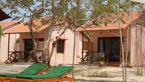 Une villa située en bord de mer, dotée d’un toit en tuiles, d’une terrasse en bois et d’un fauteuil de relaxation.