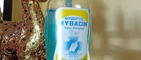 Una botella de gel hidroalcohólico con la etiqueta 'MYSEPTIC MYBACIN' sobre una estantería con una figura decorativa de ciervo dorado.