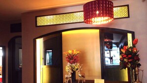 Een receptie met een donkere tafel, twee gouden hertenbeeldjes en een bloevas.