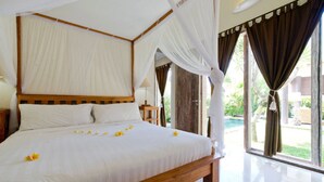A large bed with white linens and a canopy, a wooden headboard, and a view of a swimming pool through large windows. - Villa Lestari (Kerobokan)