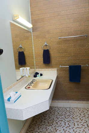 Une salle de bain avec un lavabo, un miroir, un porte-serviettes et des carreaux de sol à motifs.