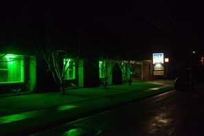 Un bâtiment avec une enseigne au néon, une entrée bien visible et une voiture garée.