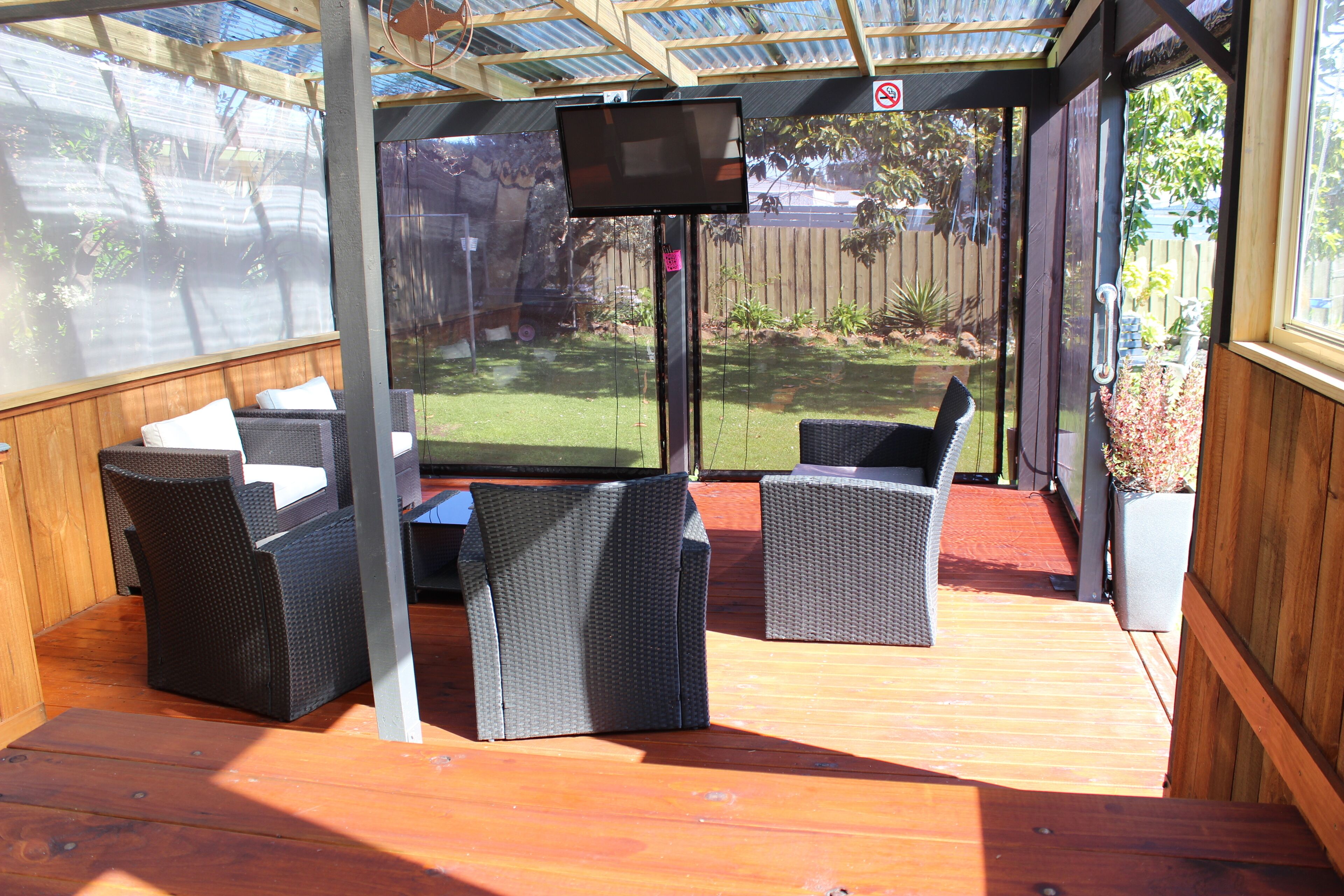 A covered patio area with wicker furniture and a flat-screen TV.