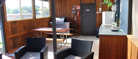 Un patio al aire libre con sillas de mimbre, una parrilla y una barra.