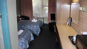 A hotel room with two beds, a desk, a chair, a TV, and a microwave. - Portland Retro Motel (Portland)