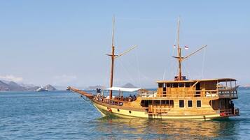 A wooden boat with multiple decks and a cabin structure, floating on calm water.