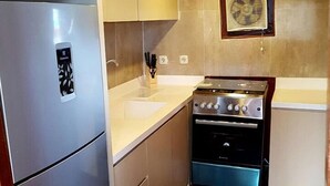 A compact kitchen with a stainless steel refrigerator, a built-in oven, and a sink. - Komodo Cruise Boat (Labuan Bajo)