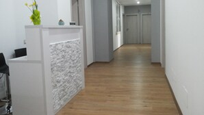 A hallway with a reception desk, a potted plant, and a staircase leading to another floor. - Brilliant Camere (Trieste)