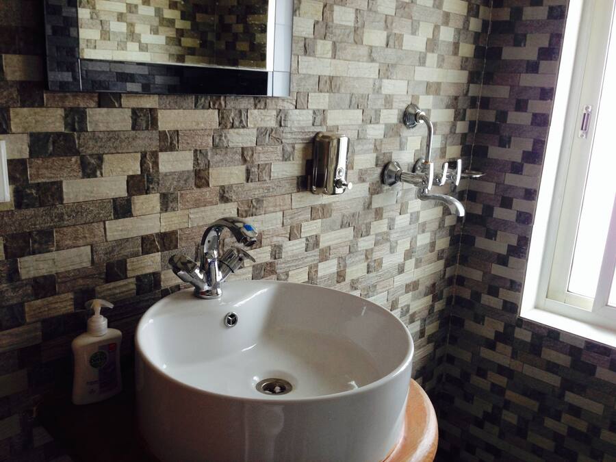 Un baño con lavamanos blanco, espejo y ducha.