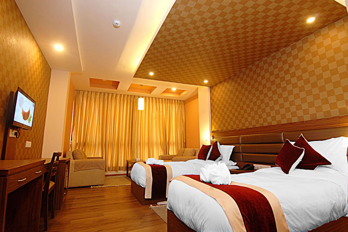 A hotel room with two beds, a desk, a chair, and a television.