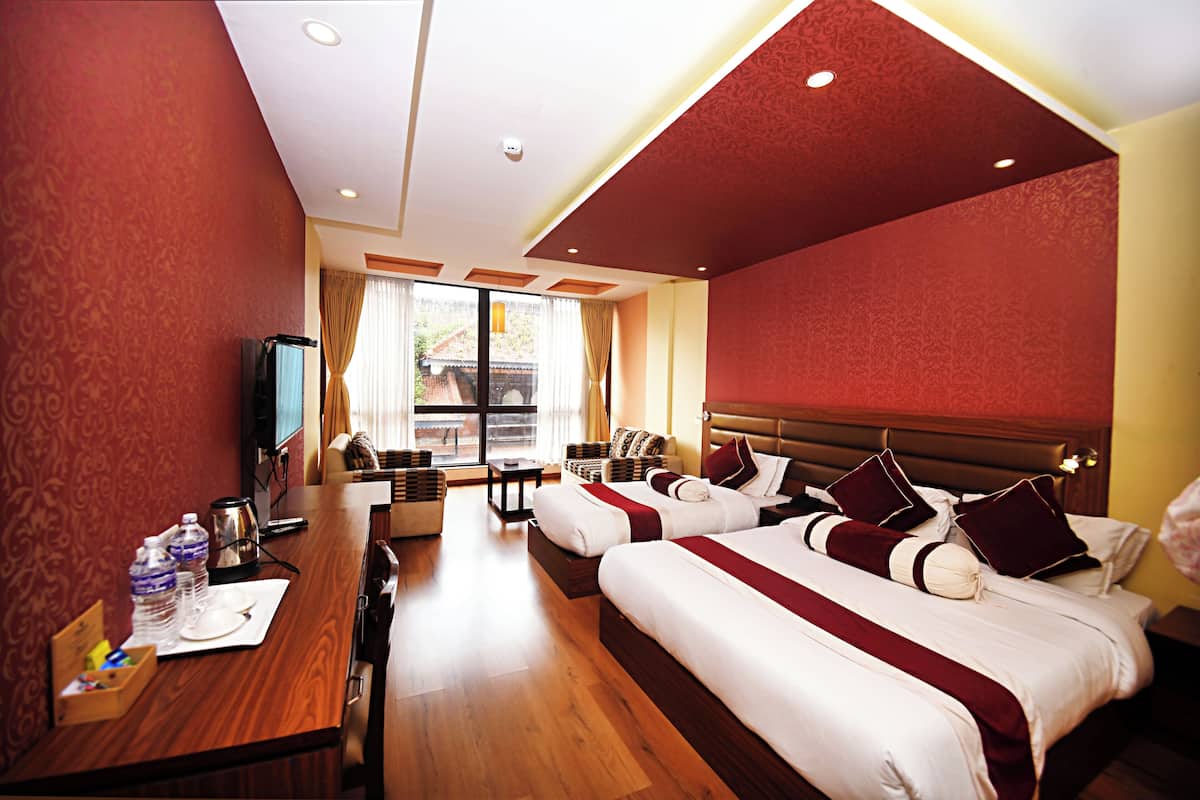A hotel room with two beds, a desk with a chair, a television, and a window with curtains.