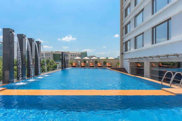 Una piscina al aire libre, sillones reclinables de piscina