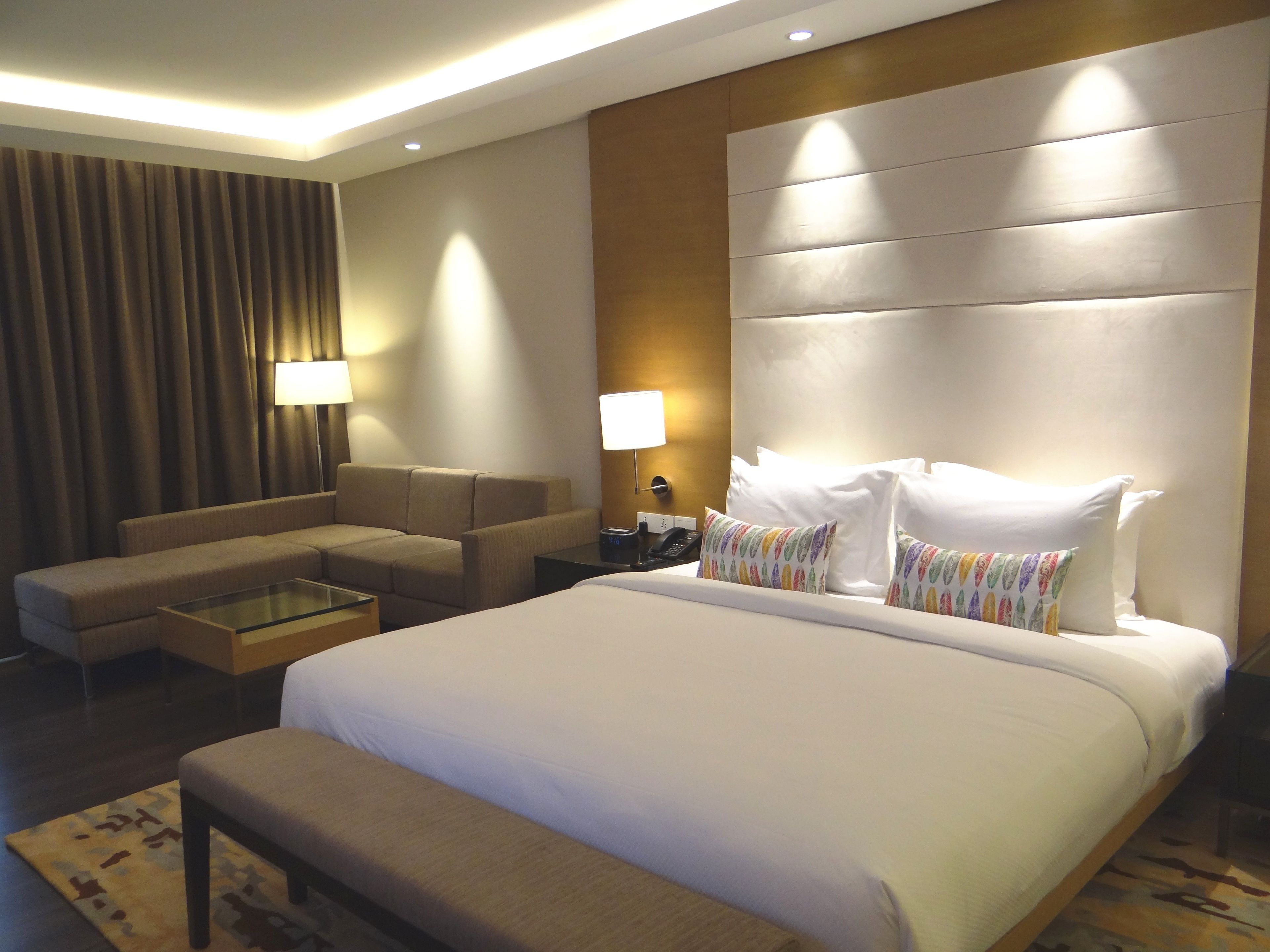 Een hotelkamer met een groot bed, een bank, een kleine tafel en twee lampen.