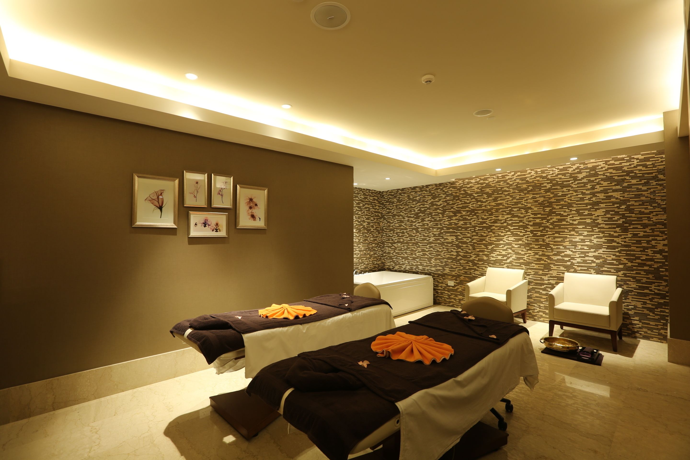 Un cuarto de spa con dos camillas de masaje, una bañera y dos sillones.