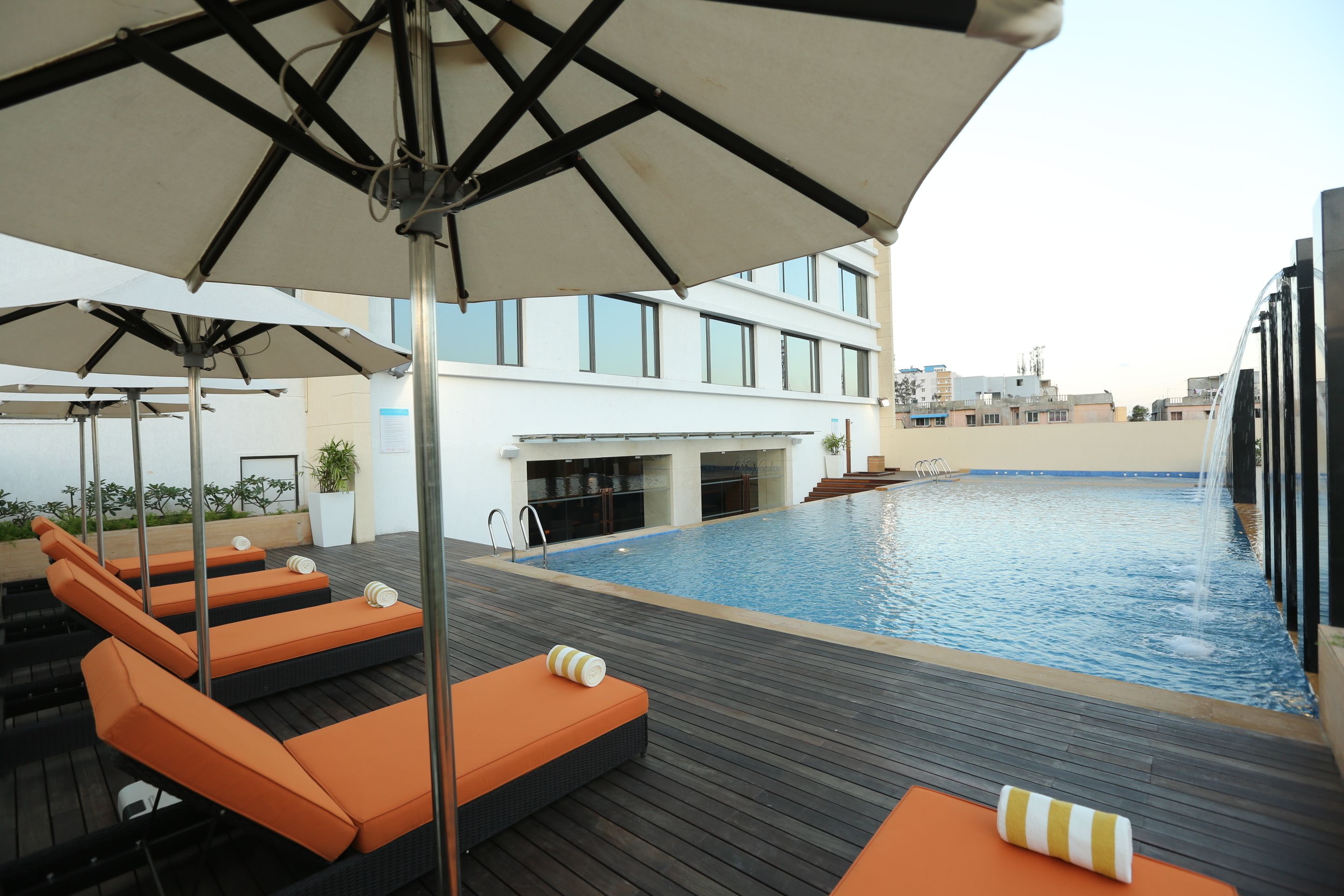 Uma área de piscina no terraço com espreguiçadeiras e guarda-sóis.