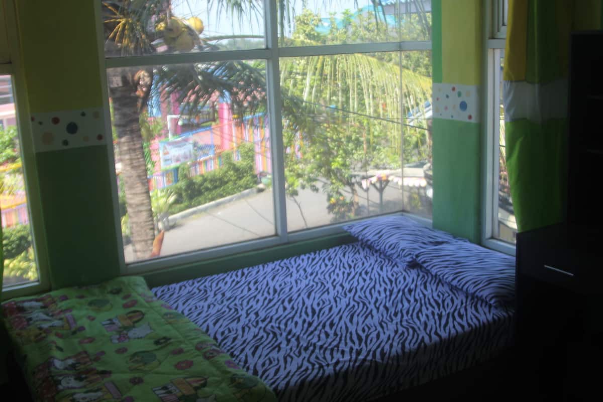 A room with a bed, a window, and a view of a colorful outdoor area.