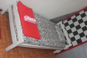 A small bed with a zebra-patterned mattress and a red blanket.
