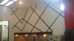 Ein Zimmer mit geometrischem Wanddesign, einem Holzpaneel als Akzent und einer Decke mit Dachfenstern und Pendelleuchten.