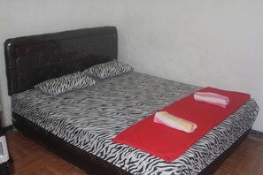 Ein Bett mit einem Zebra-Bettüberwurf, einer roten Decke und zwei Kissen.