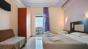A hotel room with two single beds, a sofa, a TV, and a balcony with a view. - Zante View Studios (Zakynthos)