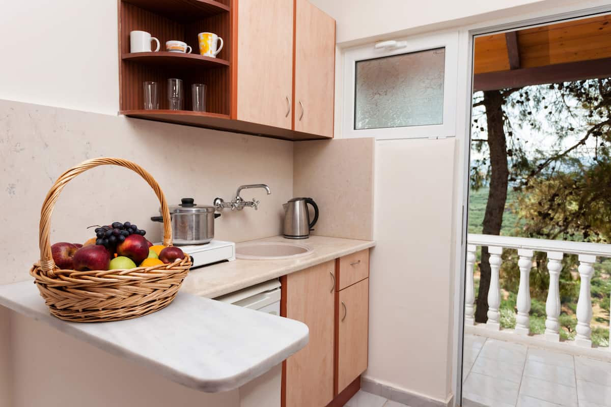 A kitchen with a sink, a coffee maker, and a fruit basket on the counter.