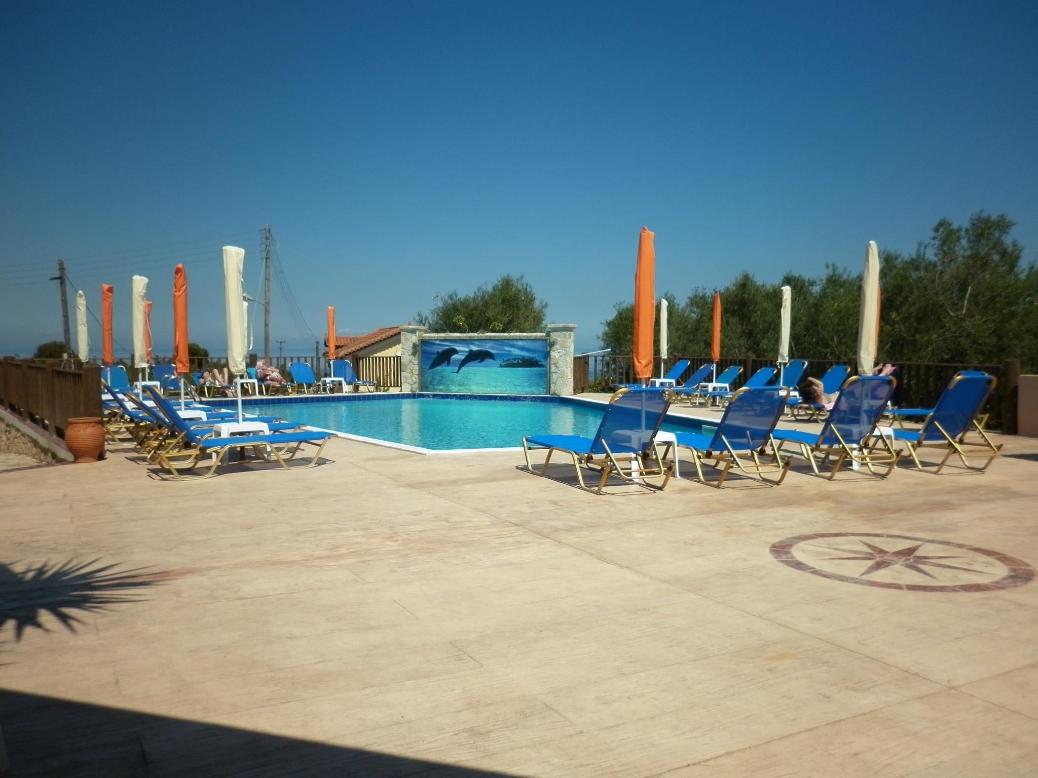 Zona de piscina amb gandules blaves i un mural de dofins.