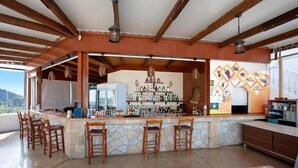 A bar area with stone countertops, wooden bar stools, and a variety of bottles. - Zante View Studios (Zakynthos)