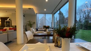 Un comedor moderno con una mesa larga dispuesta para una comida, ventanas amplias y vistas al exterior.