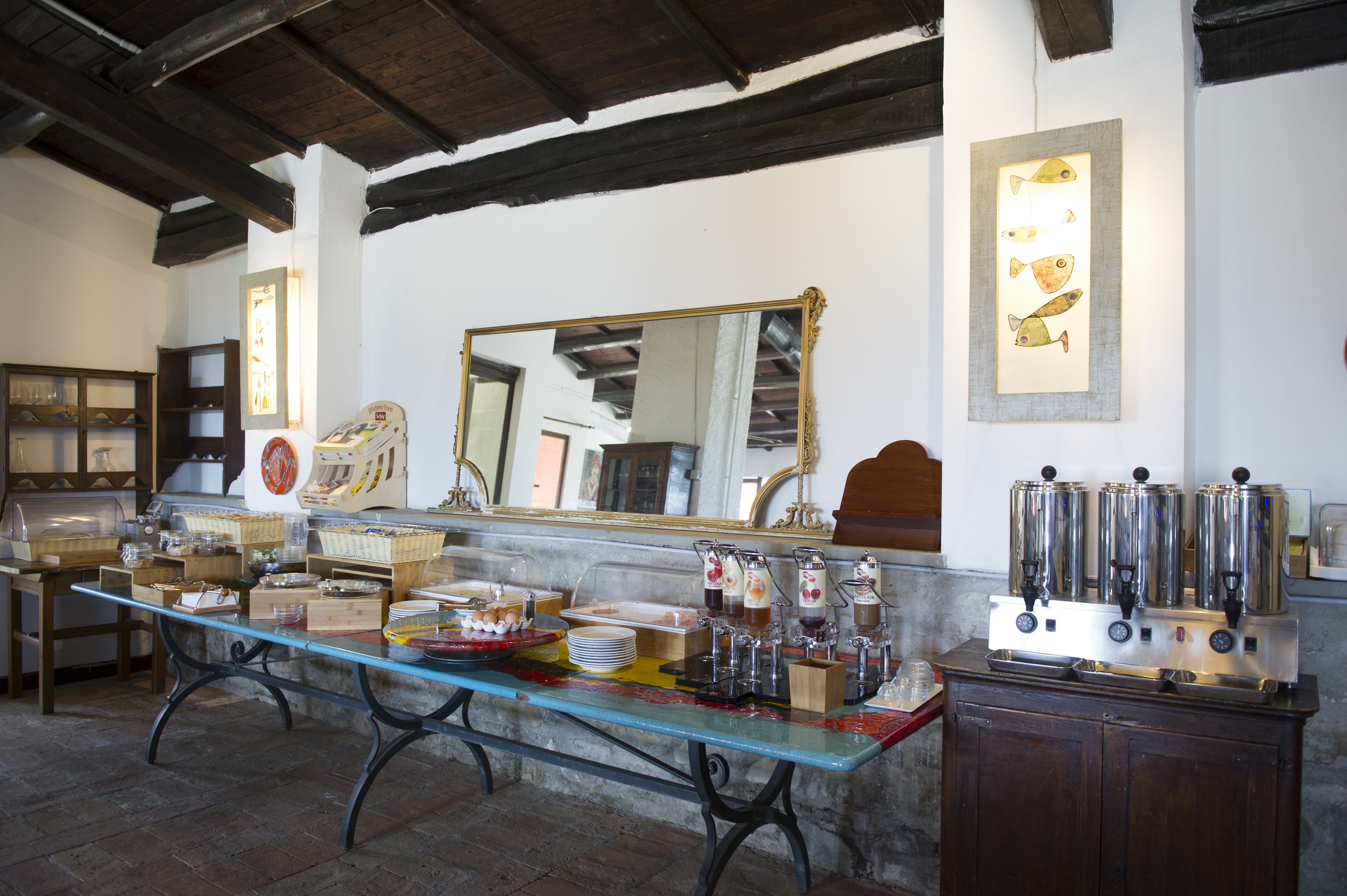 Montaje de un bufé de desayuno con una mesa de vidrio, máquinas de café y diversas opciones de comida.