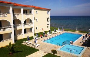 A hotel with a large pool, multiple balconies, and a view of the sea. - Maria Mare Apart-hotel (Zakynthos)