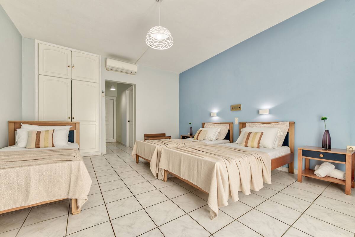 Une chambre d’hôtel avec deux lits, une armoire, une table de chevet avec une lampe et un climatiseur fixé au mur.