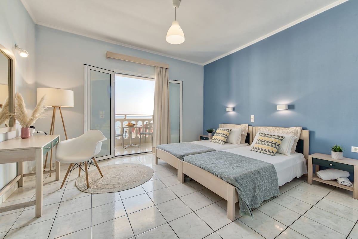 Une chambre moderne avec un grand lit, un bureau et une chaise. Elle dispose d’un balcon avec vue.