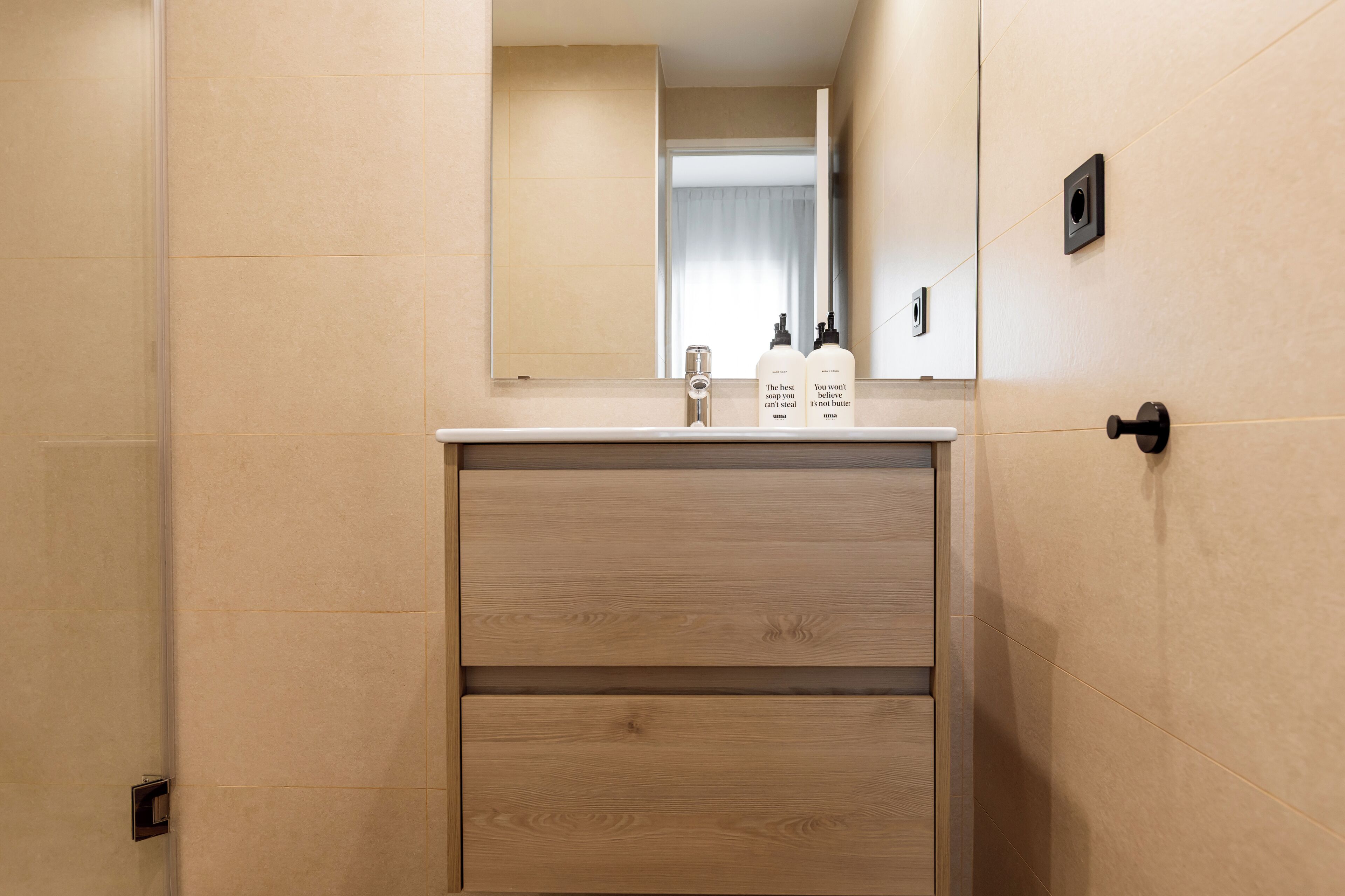 Un baño con tocador de madera, un espejo y dos botellas de jabón.