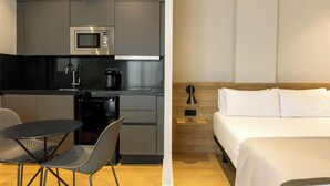 A modern kitchen with a microwave, coffee maker, and dishwasher. It also features a small dining area with a table and chairs. - Apartamentos Laforja (Barcelona)