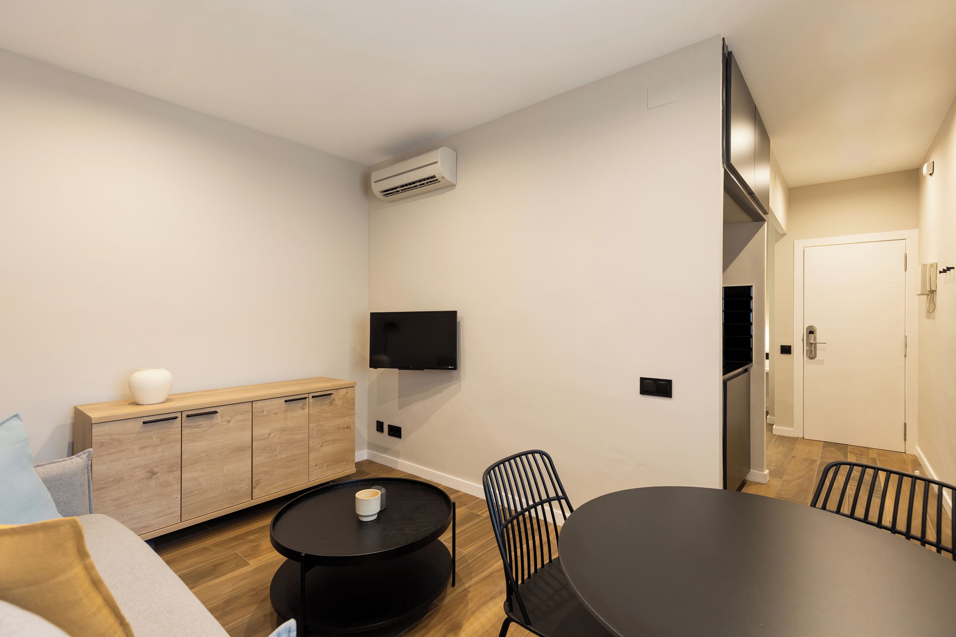 Una cocina moderna con un armario de madera, una mesa de comedor negra y una silla negra.