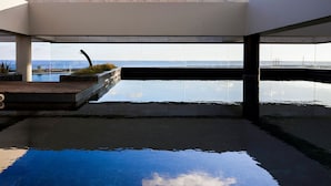 An infinity pool with a wooden deck and a view of the ocean. - Octant Ponta Delgada (Ponta Delgada)