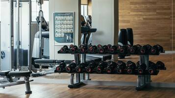 A gym with weightlifting equipment, including dumbbells and a bench press.