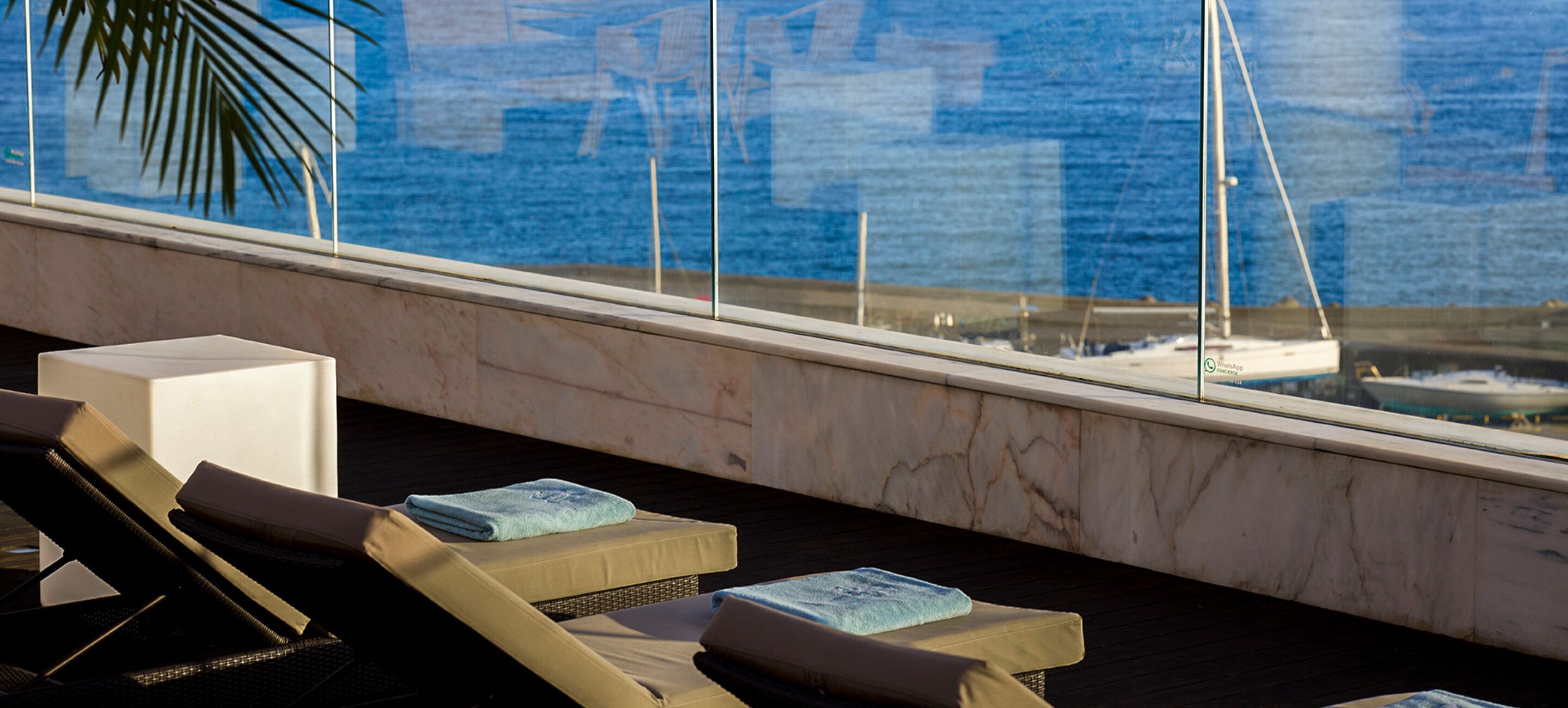 A balcony with lounge chairs and a view of the sea.