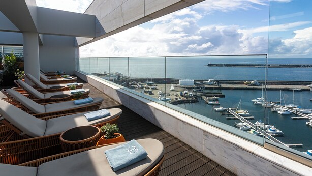 A rooftop terrace with wicker lounge chairs, a view of the marina, and a clear sky. - Octant Ponta Delgada (Ponta Delgada)