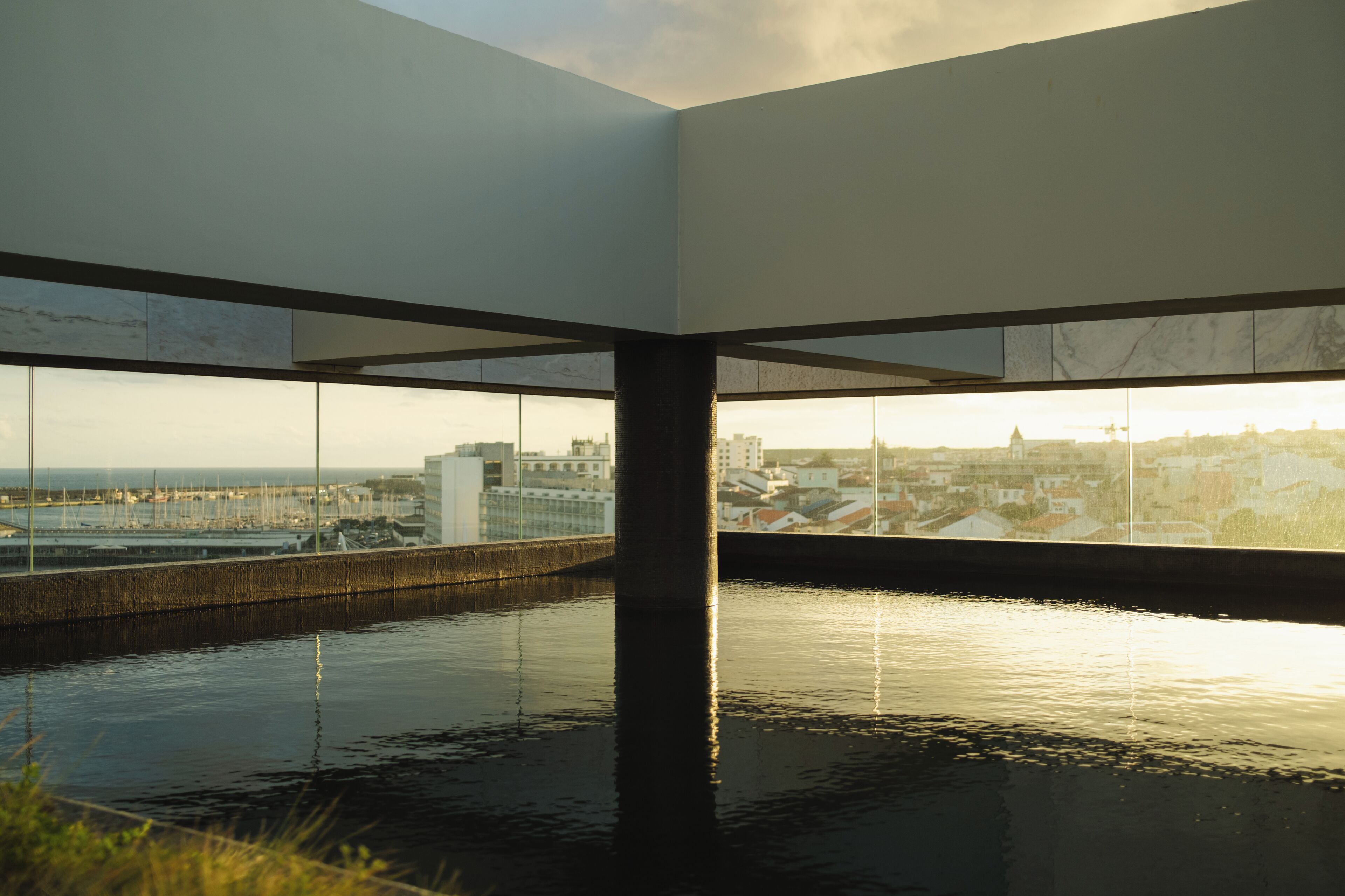 A modern interior with a large window overlooking a marina and cityscape.