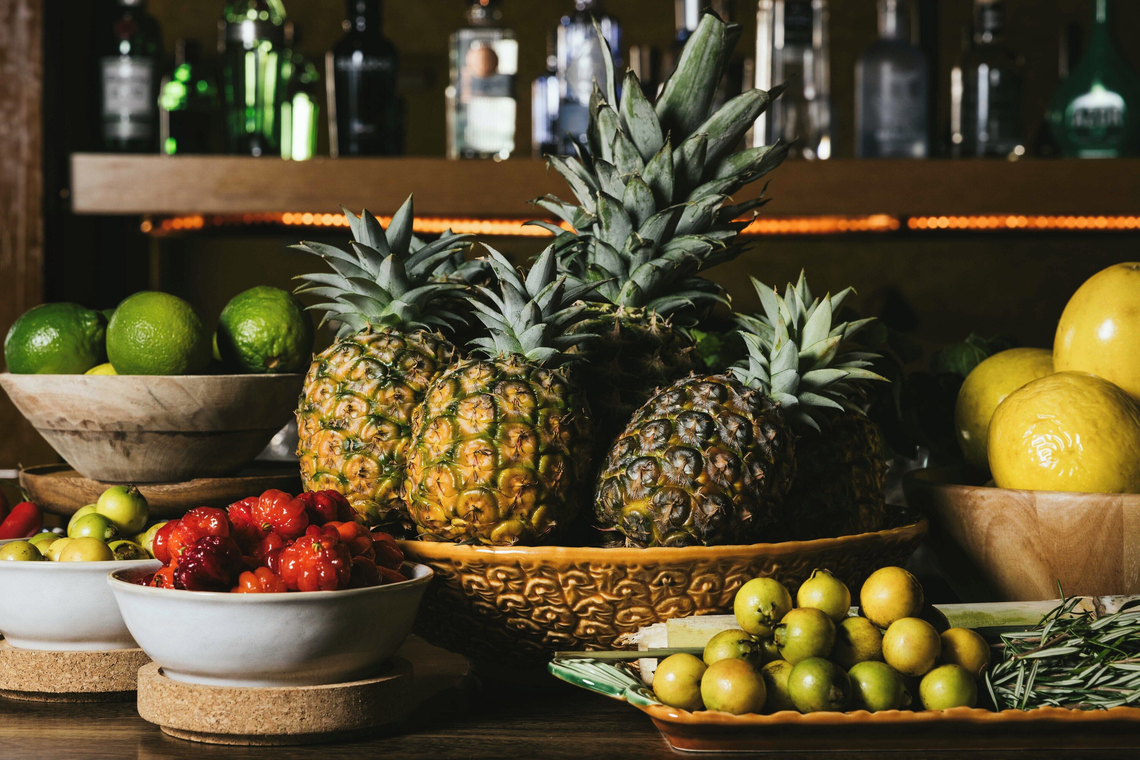 A bar setting with a variety of fruits and bottles on shelves.