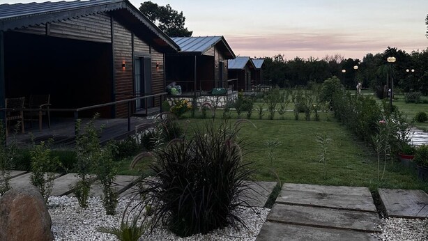A modern building with a covered outdoor area and a well-maintained garden. - Cirali Simge Holiday Houses (Kemer)