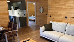 A modern interior with a wooden ceiling, a sofa, a coffee table, and a dining area with chairs. - Cirali Simge Holiday Houses (Kemer)