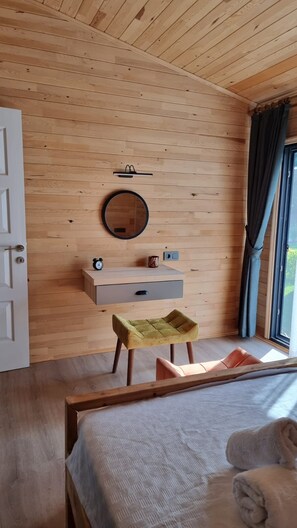 A wooden-paneled room with a bed, a bedside table, a mirror, and a window with curtains.