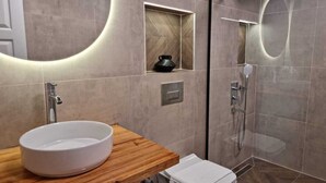 A modern bathroom with a large sink, a small toilet, and a glass-enclosed shower area. - Cirali Simge Holiday Houses (Kemer)