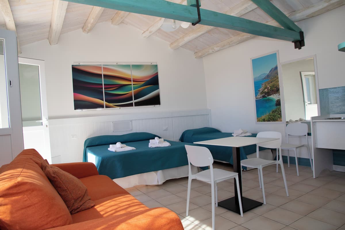 Una habitación con dos camas, una mesa de comedor y un sofá.
