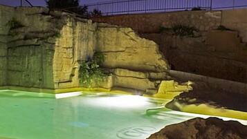 En swimmingpool med en klippefoldning og et hegn i baggrunden.