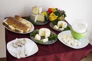 Una mesa con varios quesos, pan y un tazón de arroz.